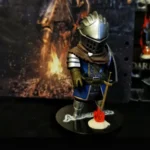 Dark Souls Statue: Elite Knight Oscar in blue armor, metal helmet, flaming torch, ancient ruins backdrop, dark fantasy aesthetic.